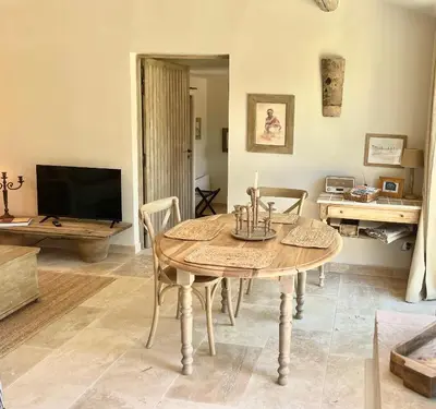 a dining room with a table and a tv at Le Mas Natán in Gordes
