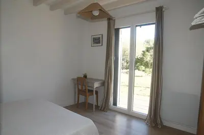 a bedroom with a bed and a desk next to a window at Sous le figuier in La Roque-sur-Pernes