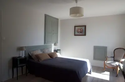 a bedroom with a bed and a lamp and a chair at Sous le figuier in La Roque-sur-Pernes