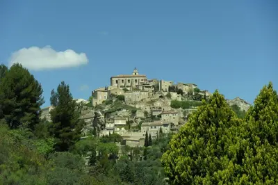 a village on top of a hill with trees at Bastide De La Lézardière in Fontaine-de-Vaucluse