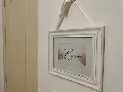 a white picture frame with the word love on a wall at Chaleureux Appartement RDC 49 m2 avec Jardin in Aix-en-Provence