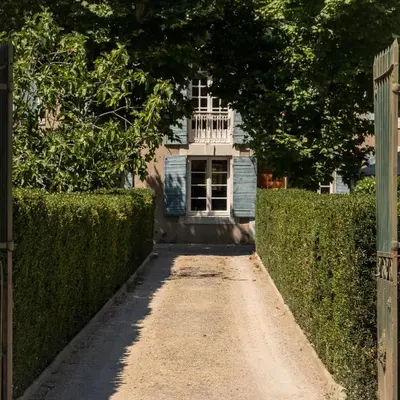 a dirt road leading to a house with a fence at La maison du bonheur in Pélissanne