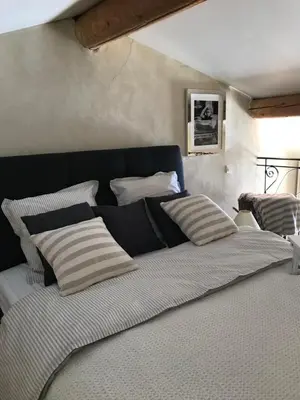 a bedroom with a large bed with striped pillows at Les goûts et les couleurs in Cucuron