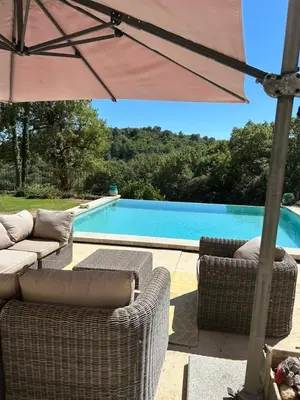 a patio with chairs and an umbrella next to a swimming pool at Les goûts et les couleurs in Cucuron