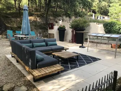 a patio with a couch and a table and an umbrella at Les goûts et les couleurs in Cucuron