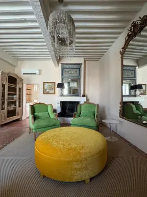 a living room with a yellow ottoman and two green chairs at Atlantes de Saint Saturnin in Saint-Saturnin-les-Apt
