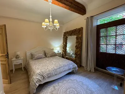 a bedroom with a bed with a mirror and a chandelier at Atlantes de Saint Saturnin in Saint-Saturnin-les-Apt