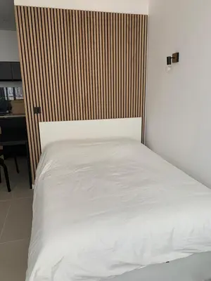 a bedroom with a white bed with a wooden headboard at Studio au cœur d Aix en Provence in Aix-en-Provence