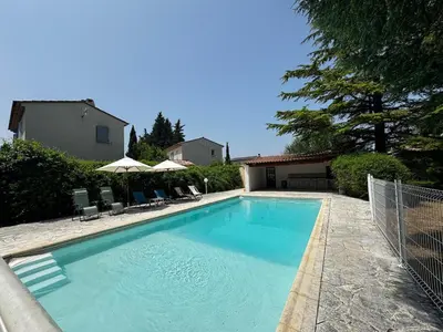 a swimming pool with chairs and umbrellas next to a house at La Provençale - Piscine - Chambres climatisées in Aubignan