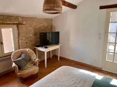 a bedroom with a tv and a chair and a table at Charmante maison de village dans le Luberon in Beaumont-de-Pertuis