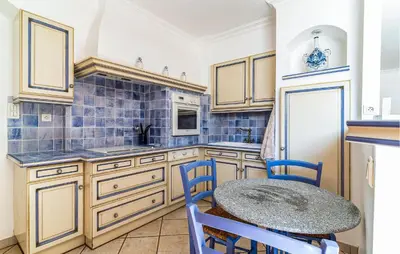 a kitchen with a table and blue tiles at 2 Bedroom Amazing Home In Noves in Noves