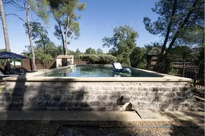 a pool in a stone wall with a chair in it at Gite Lucie in Carpentras