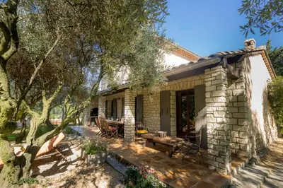a stone house with a patio and trees at Gite Lucie in Carpentras