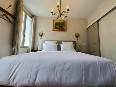 a large white bed in a bedroom with a chandelier at Appartement Superbe 2 personnes Coeur de ville l'Isle sur Sorgue in LʼIsle-sur-la-Sorgue