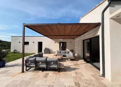 a patio with couches and a wooden pergola at Villa Noyau & Pépin in Rognes
