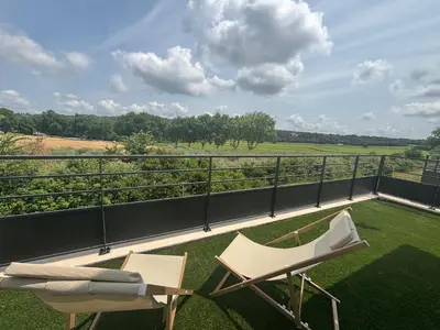 a balcony with two chairs and a view of a field at Villa Noyau & Pépin in Rognes
