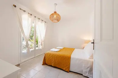 a white bedroom with a bed and a window at Gordes Villa avec piscine chauffée et privée , jacuzzi et pétanque calme in Gordes