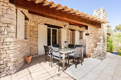 a patio with a table and chairs on a stone building at Gordes Villa avec piscine chauffée et privée , jacuzzi et pétanque calme in Gordes