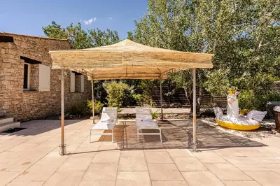 a group of chairs under a pavilion in a yard at Gordes Villa avec piscine chauffée et privée , jacuzzi et pétanque calme in Gordes