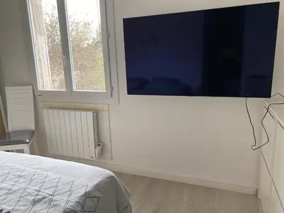 a bedroom with a large flat screen tv on a wall at Grand appartement spacieux in Sénas
