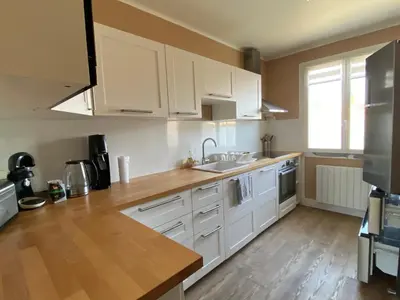 a kitchen with white cabinets and a wooden floor at Grand appartement spacieux in Sénas