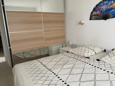 a bed with a black and white comforter and pillows at Grand appartement spacieux in Sénas