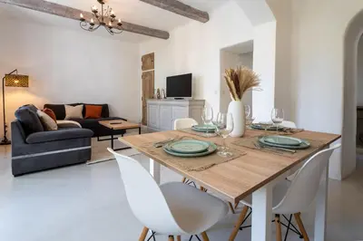 a living room with a wooden table and white chairs at L’oustaou de Ventabren Village Square in Ventabren