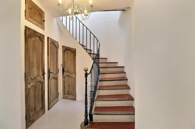 a staircase with wooden doors and a chandelier at L’oustaou de Ventabren Village Square in Ventabren