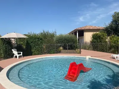 a pool with two red chairs in the water at Maison aux Demeures du Ventoux Adaptée PMR in Aubignan
