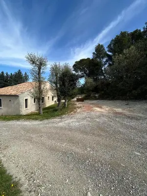 an old house on a gravel road next to trees at Charmante maison avec piscine et grand jardin in LʼIsle-sur-la-Sorgue