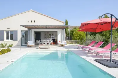 a swimming pool with chairs and a red umbrella at Villa Cali - Air-conditioned, Pool, Heart Village in Cabrières-dʼAvignon