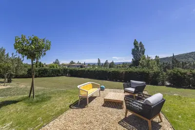 a patio with two chairs and a table in a yard at Villa Vue Luberon in Gordes