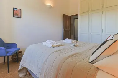 a bedroom with a large bed with a blue chair at Villa Vue Luberon in Gordes