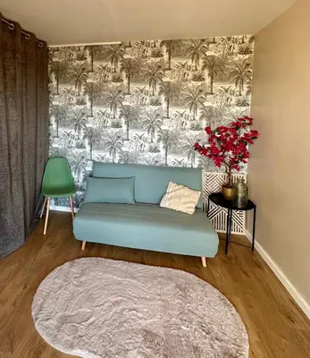 a living room with a blue couch and palm trees mural at 10 mn gare TGV Aix, parking gratuit & check-in autonome in Aix-en-Provence