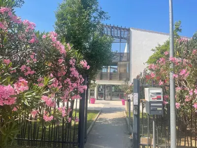 a gate in front of a building with pink flowers at Studio cosy, résidence de tourisme avec piscine in Aix-en-Provence