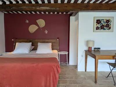 a bedroom with a bed with a red wall at Mas traditionnel à Gordes en pleine nature in Gordes