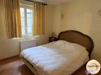a bedroom with a white bed with a large window at Villa Provençale avec piscine in Pernes-les-Fontaines