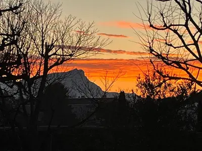 a sunset with trees in front of a mountain at Appartement Aix, résidence calme avec piscine in Aix-en-Provence