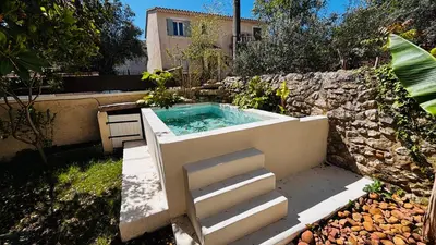 a hot tub in a garden with a stone wall at Le Beldi, Mas de Village 1870 in Saint-Saturnin-lès-Avignon