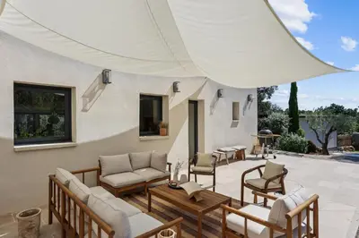 a patio with couches and chairs under a white umbrella at Big Modern Villa Ste Victoire 10min CityCenter Aix in Saint-Marc-Jaumegarde