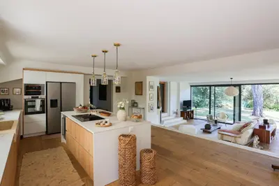 a kitchen and living room with white walls and wood floors at Big Modern Villa Ste Victoire 10min CityCenter Aix in Saint-Marc-Jaumegarde