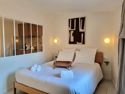 a bedroom with a white bed with a bench on it at MAYU MAYU - cocon centre-ville climatisation in Aix-en-Provence