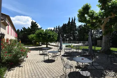 a group of tables and chairs with umbrellas at Hôtel PRATO PLAGE in Pernes-les-Fontaines
