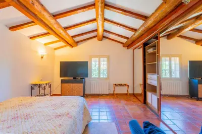 a bedroom with a bed in a room with wooden ceilings at Le Mas des lys - Guest houses au coeur de la Provence dans un parc paysagé avec piscine, sauna et boulodrome in Grans