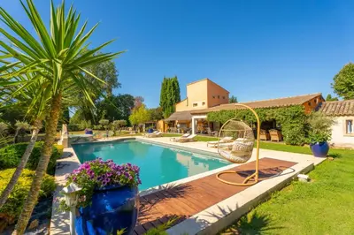 a swimming pool with a swing in a yard at Le Mas des lys - Guest houses au coeur de la Provence dans un parc paysagé avec piscine, sauna et boulodrome in Grans