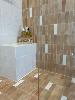 a tiled shower with two bottles on a shelf at La Réserve Villa in Aix-en-Provence