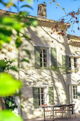 a wooden table with chairs under a tree at Montjoia in LʼIsle-sur-la-Sorgue