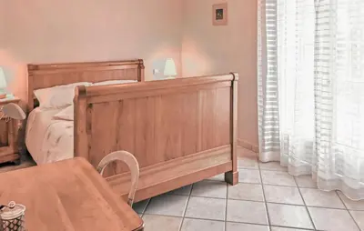 a bedroom with a wooden bed and a chair at Nice Home In Carpentras in Carpentras