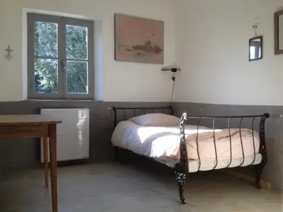 a bedroom with a bed and a desk and a window at La Grande Bastide in Vaugines