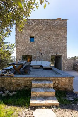 a stone building with a patio and a table at Evasion Luberon in Murs